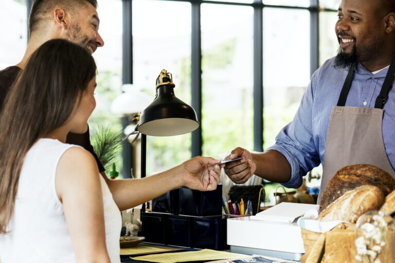 Kundin und Kunde zahlen in Bäckerei kontaktlos